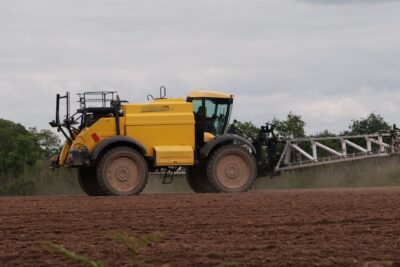 Tractor spraying pesticides on farmland causing agricultural pollution